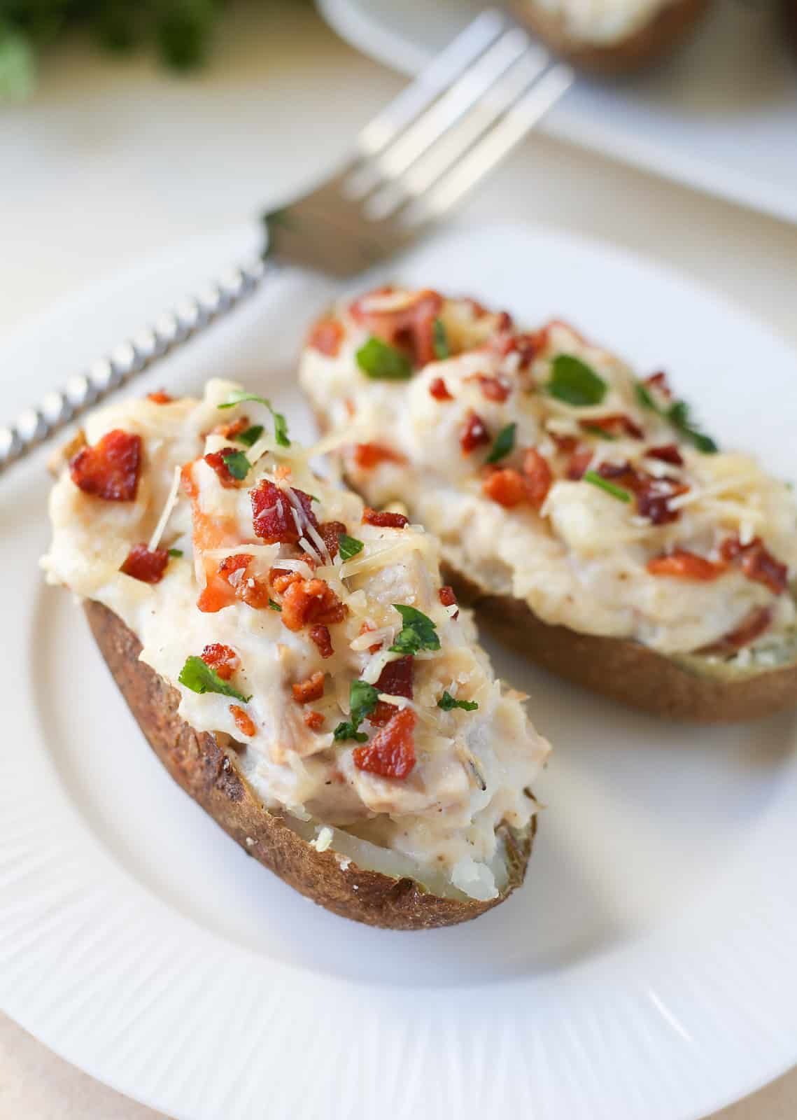 Two chicken alfredo twice baked potatoes on a white plate