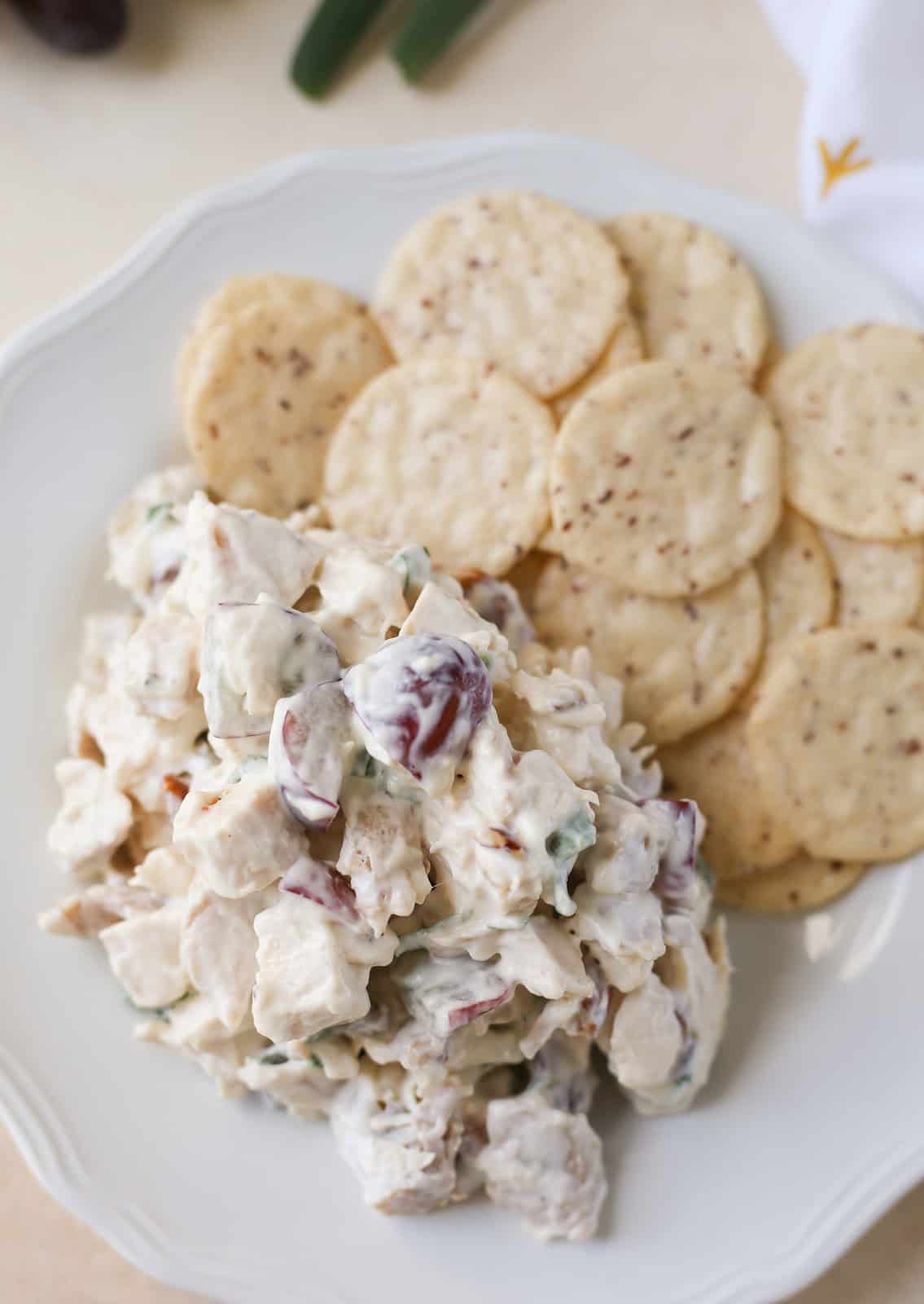 Overhead shot of chicken salad with grapes, pecans, and green onions. Served with crackers.