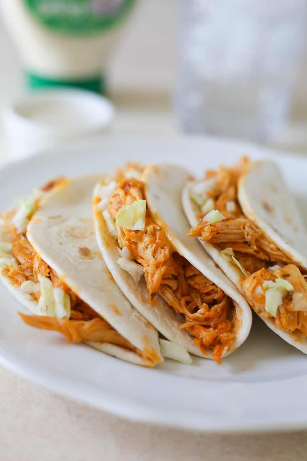 Slow Cooker Buffalo Chicken Tacos are a fast and flavorful dinner that calls for just a few simple ingredients. Flour tortillas filled with spicy shredded chicken, cheese, and whatever toppings you want!