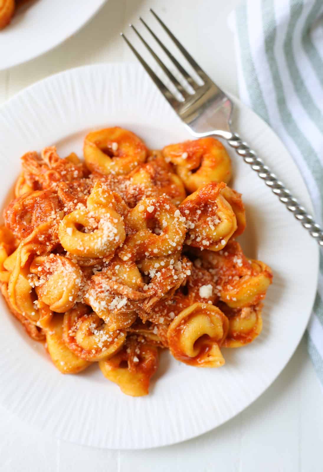 overhead shot of tortellini and shredded chicken in pasta sauce with grated Parmesan on top