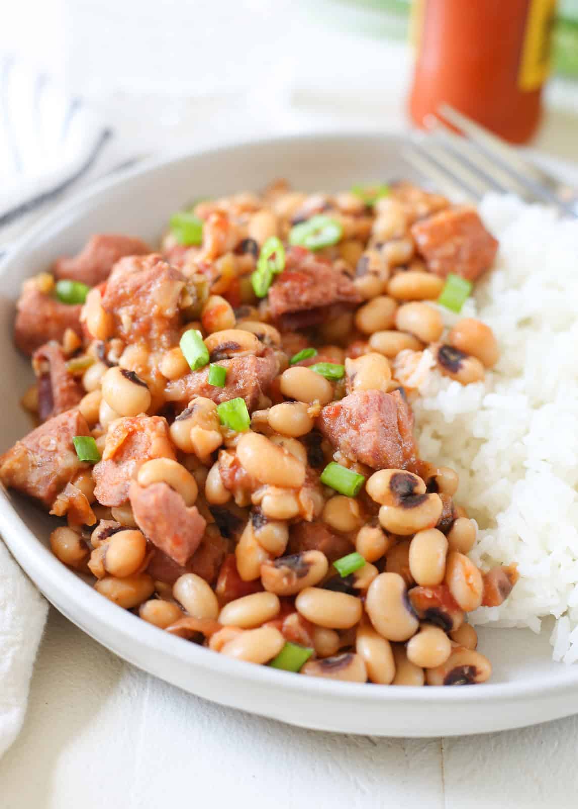 Classic southern Hoppin' John is made with black eyed peas, smoked sausage, vegetables, and served with rice. It's traditionally enjoyed on New Years Day for good luck throughout the year.