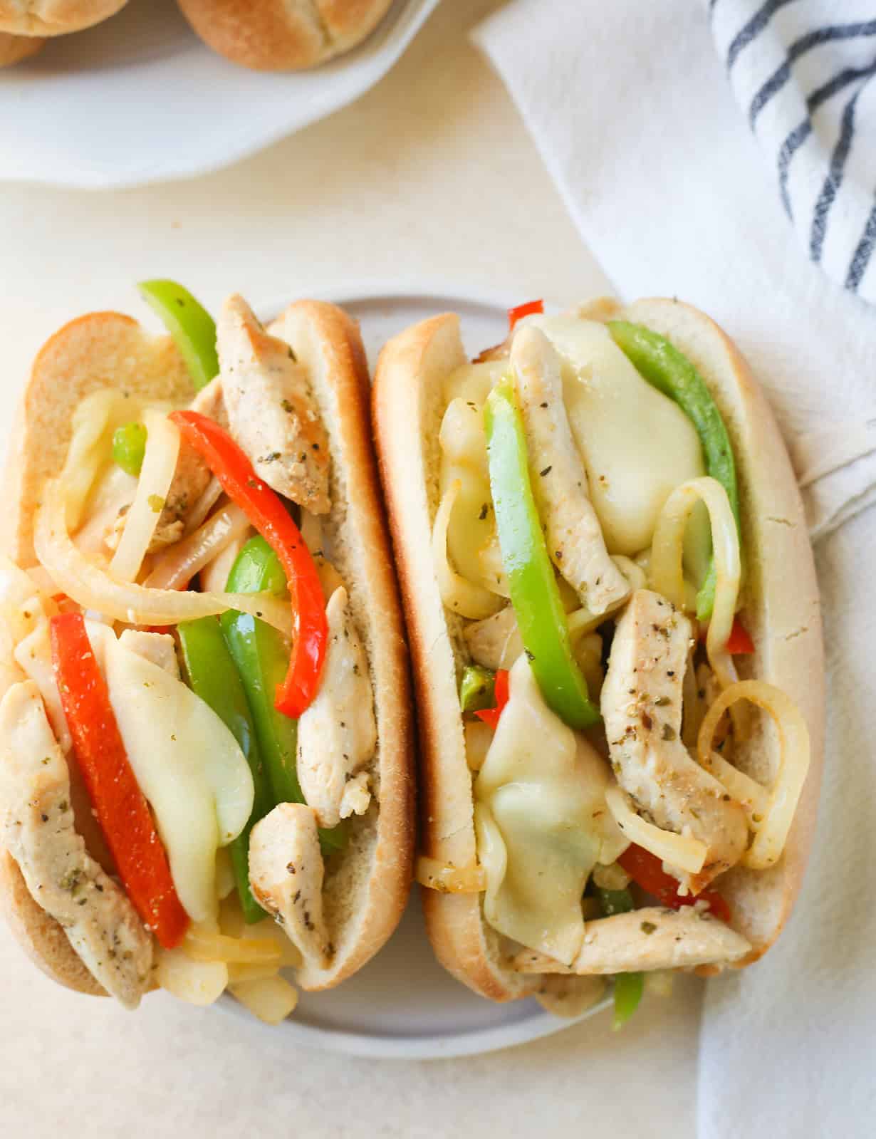 overhead photo of 2 chicken cheesesteaks in sub rolls with provolone cheese