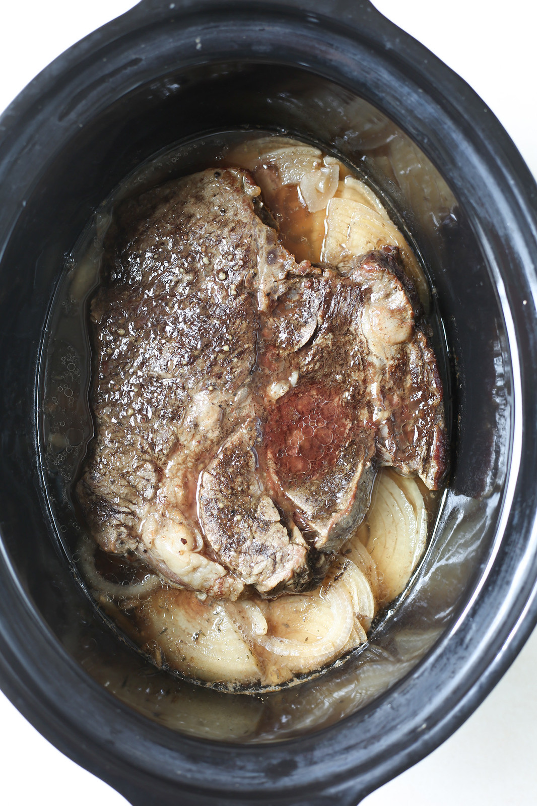 Overheat shot of a pot roast and onions in a slow cooker